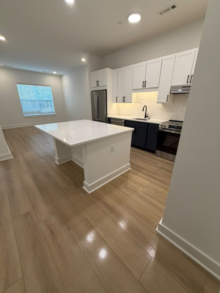 Spotless open-plan kitchen with white quartz island after a Sandi's cleaning
